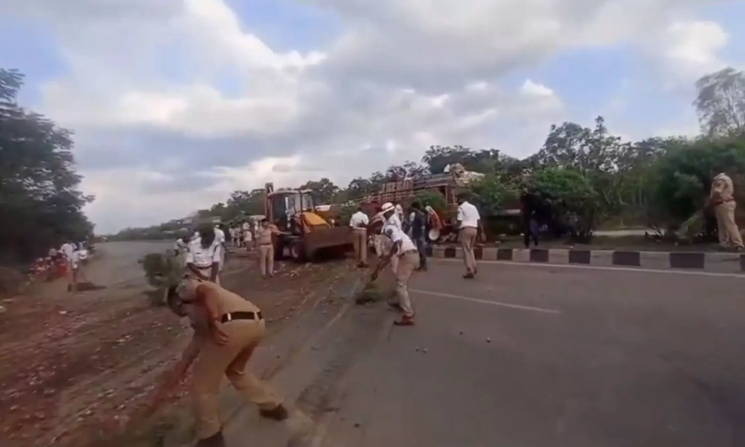 Police officers sweep road to clear traffic after truck collision